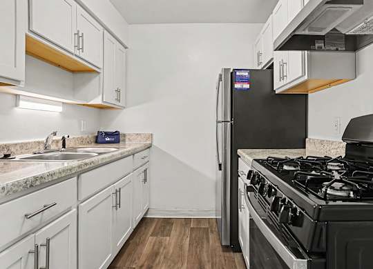 Galley kitchen with white cabinets and granite countertops at Fairlane Apartments, Michigan, 49037