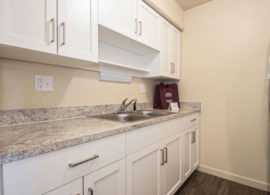 a kitchen with white cabinets and a sink and a refrigerator at Old Farm Apartments, Elkhart, Indiana