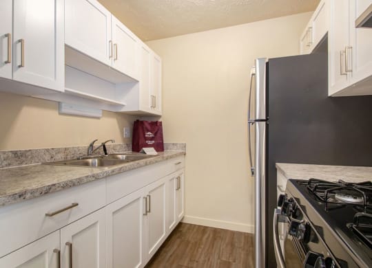 a kitchen with white cabinets and a stainless steel refrigerator at Old Farm Apartments, Elkhart, Indiana