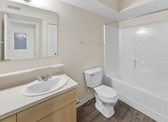 A white bathroom with a toilet, sink, and bathtub at Fieldstream Apartment Homes in IA 50023