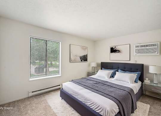 A bedroom with a bed, nightstands, and pictures on the wall.