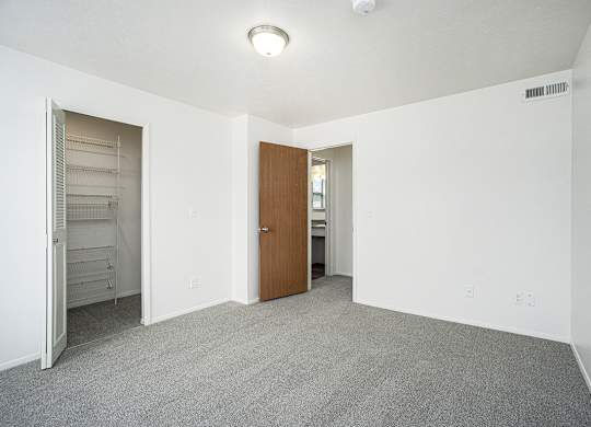 A bedroom with a carpeted floor and a walk-in closet with wardrobe organizers at Foxwood and The Hermitage in Portage, MI