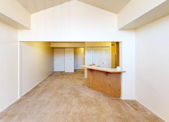 A living room with a cathedral ceiling and plush carpeting at Foxwood and The Hermitage, Portage, MI