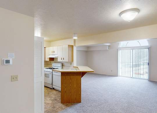 A kitchen and an enlarged living room with a cathedral ceiling at Foxwood and The Hermitage, Portage, MI