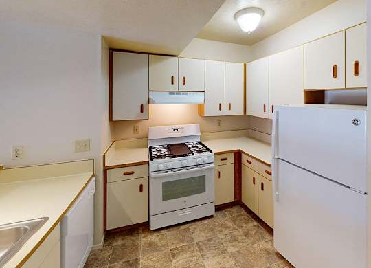 A kitchen with white appliances and wooden cabinets at Foxwood and The Hermitage, Portage, MI