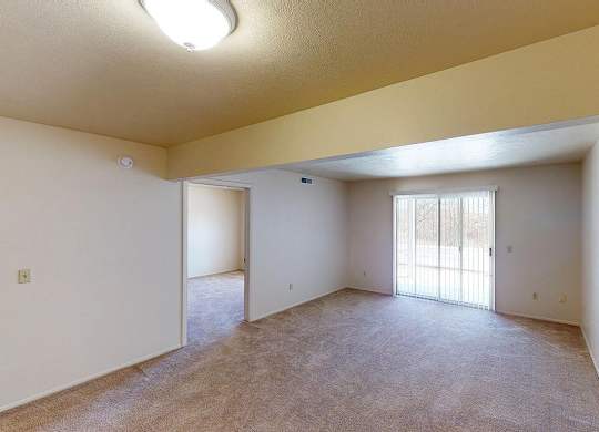 A living room with a slider to a patio and plush carpet at Foxwood and The Hermitage, Portage, MI