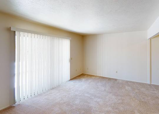 A large living room with a carpeted floor and a window with blinds at Foxwood and The Hermitage, Portage, MI