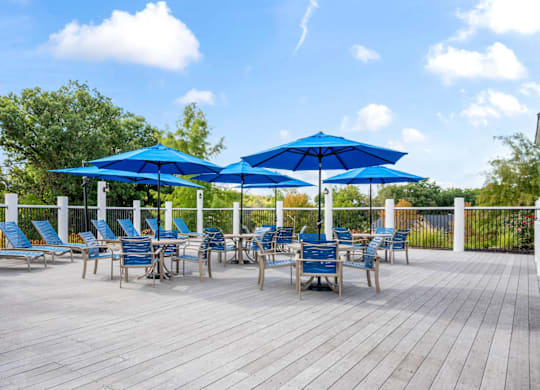 A wooden deck with blue umbrellas and chairs at Timberlane Apartments, Illinois, 61615