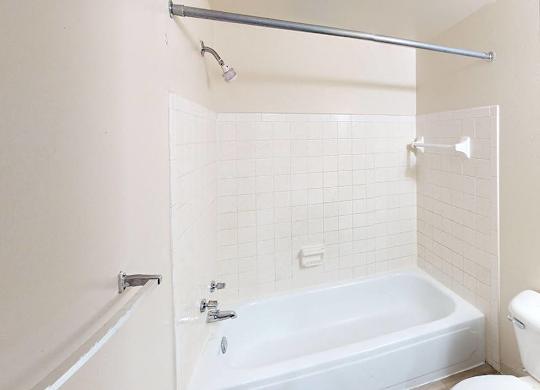 A full bathroom with a tub, toilet, and shower at Glen Oaks Apartments, Michigan, 49442