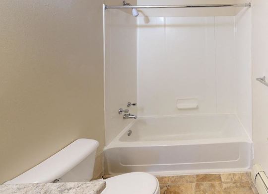 A bathroom with a toilet, tub, and shower at Glen Oaks Apartments, Michigan, 49442