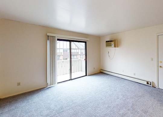 A carpeted living room with a slider to a private balcony at Glen Oaks Apartments, Michigan, 49442