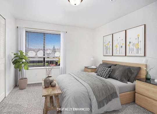 A bedroom with a large window, bed, and a closet at Glenn Valley Apartments in Battle Creek, MI