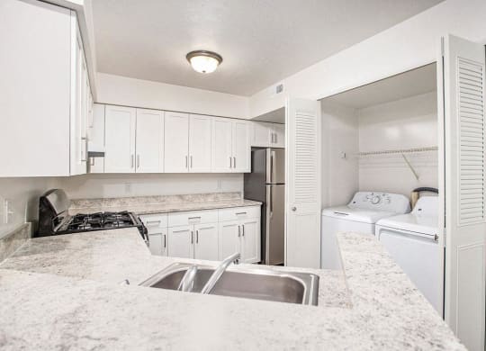 a kitchen with white cabinets and a washer and dryer at Glenn Valley Apartments in Battle Creek, MI