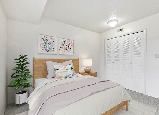 A bedroom with a large closet, bed, and a potted plant at Granada Apartments, Jackson, 49202