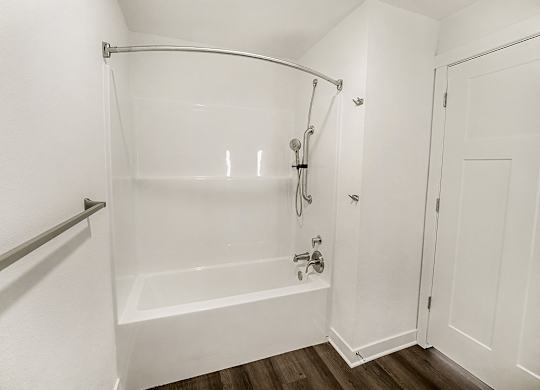 A white bathroom with a bathtub and a shower at The Grove Apartment Homes in Lincoln, NE