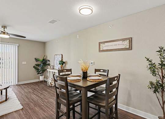 A dining room with a table set for four and a plant on the side at The Grove Apartment Homes, Nebraska