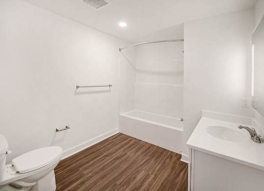 A white bathroom with hard-surface flooring at The Grove Apartment Homes in Lincoln, NE