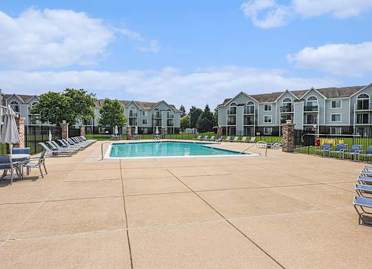 A large outdoor swimming pool surrounded by lounge chairs at Gull Prairie/Gull Run Apartments and Townhomes, Kalamazoo