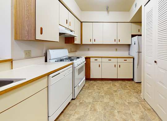 A kitchen with white appliances and washer/dryer at Gull Prairie/Gull Run Apartments and Townhomes, Kalamazoo, Michigan