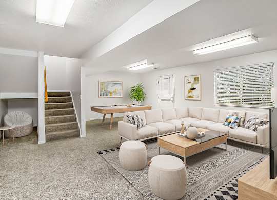 A basement recreation room with a grey carpet and a sofa at Gull Prairie/Gull Run Apartments and Townhomes, Michigan, 49048