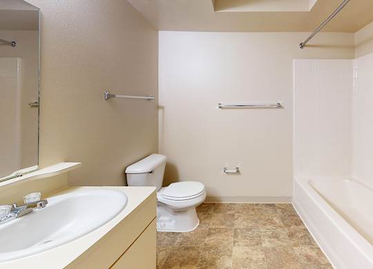 A bathroom with a toilet, sink, and bathtub at Gull Prairie/Gull Run Apartments and Townhomes, Kalamazoo, Michigan