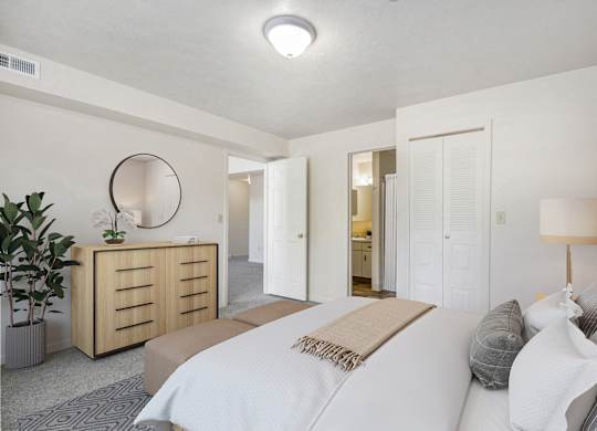 A bedroom with a large bed, a walk-in closet, and an ensuite bathroom at Gull Prairie/Gull Run Apartments and Townhomes, Michigan, 49048