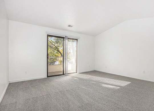 living room with a cathedral ceiling and sliding glass door to a balcony at Hampton Lakes Apartments, Michigan, 49534