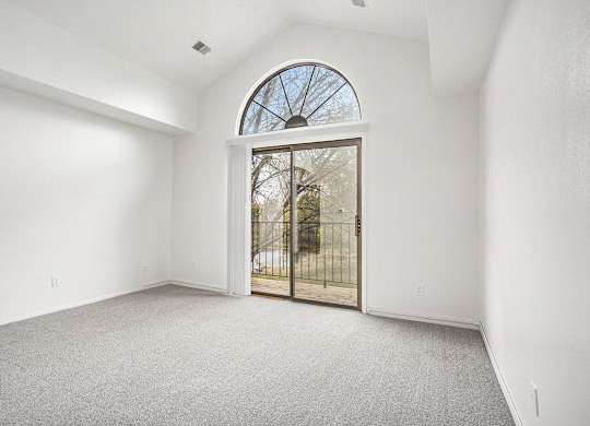 a living room with a cathedral ceiling and door to a balcony at Hampton Lakes Apartments, Michigan, 49534