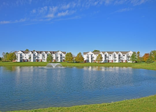 a lake with a fountain in front of a building at Heatherwood Apartments, Grand Blanc