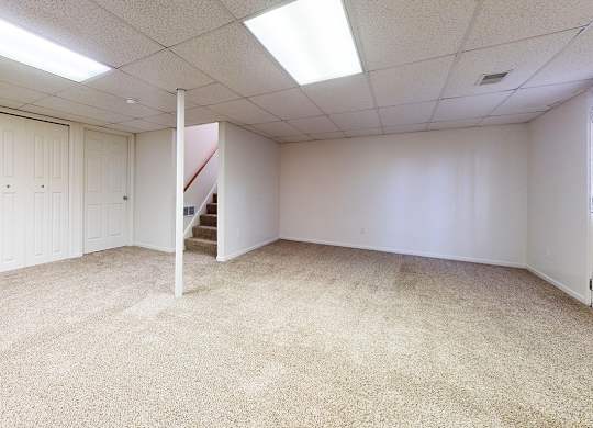 A basement recreation room with white walls and carpeted floor at Foxwood and The Hermitage, Michigan