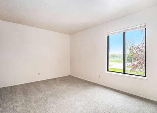 a bedroom with a large window and a carpeted floor at Hickory Village Apartments, Mishawaka, Indiana