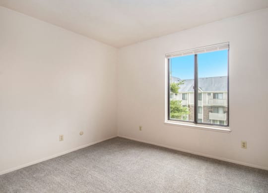 a bedroom with a large window and a carpeted floor at Hickory Village Apartments, Mishawaka, IN