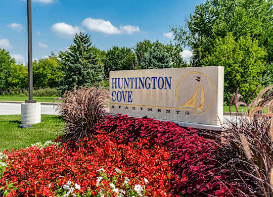 A sign for Huntington Cove Apartments is surrounded by flowers