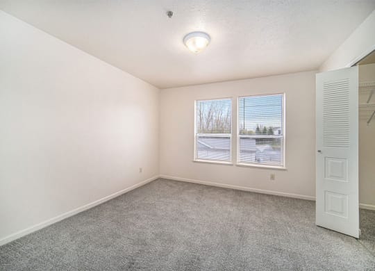 Large bedroom with a walk-in closet and two windows at Hurwich Farms Apartments, Indiana