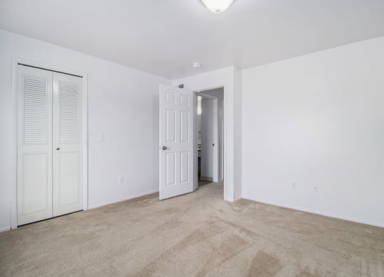 an empty living room with white walls and a door to a hallway at Hurwich Farms Apartments, Indiana