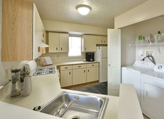 a kitchen with a sink and a washing machine at Heatherwood Apartments, Grand Blanc