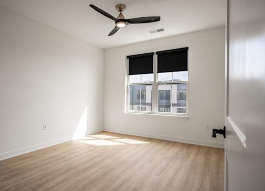 A room with a ceiling fan and a window with blinds.
