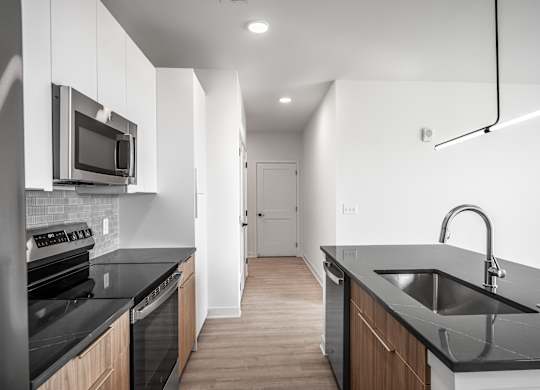 A modern kitchen with black countertops and wooden cabinets.