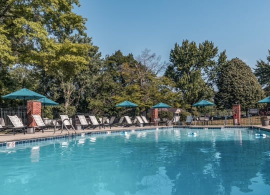 a swimming pool with chairs and umbrellas at Polo Run Apartments, Indiana