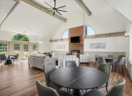 A large black table surrounded by chairs in a room with a brick fireplace at Indian Lakes Apartments, Mishawaka, Indiana