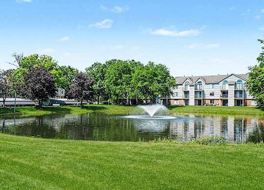 A fountain in the middle of a pond in front of a building at Indian Lakes Apartments, Mishawaka, Indiana