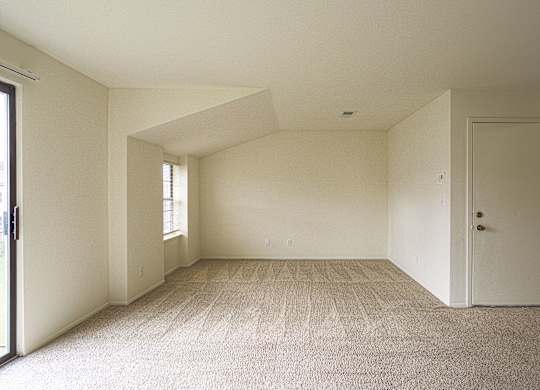A room with a carpeted floor and a door on the right side.