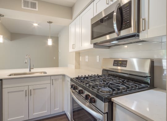 a kitchen with white cabinets and stainless steel appliances at Hillside Apartments, Wixom, MI