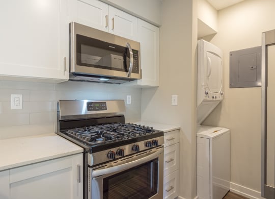 a kitchen with white cabinets and stainless steel appliances at Hillside Apartments, Wixom, MI