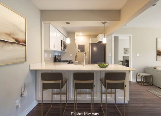 a kitchen with white cabinets and a large island with four stools at Hillside Apartments, Wixom, MI, 48393