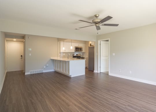 an empty living room with a kitchen in the background at Hillside Apartments, Michigan, 48393