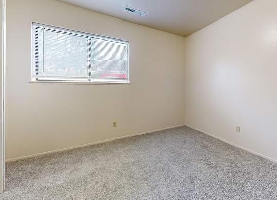 A bedroom with a window and carpeted floor at Irish Hills Apartments, South Bend, Indiana