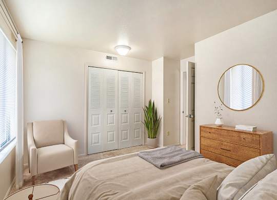 A bedroom with a bed, chair, a closet and a dresser at Irish Hills Apartments, South Bend, Indiana