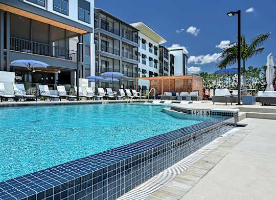 A swimming pool in front of a hotel with a blue sky in the background at Ironwood Flats Apartments, Florida