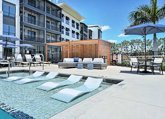 A pool area with sun loungers and a wooden structure at Ironwood Flats Apartments, Brandon, FL